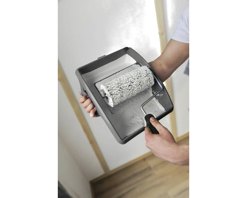 Une personne tient un rouleau à peinture et un bac à peinture avec de la peinture pour peindre