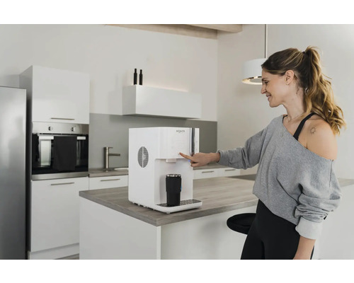 Femme utilisant un distributeur d''eau dans une cuisine moderne