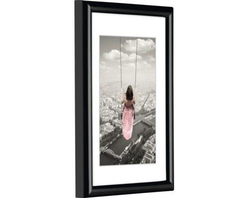 Tableau mural encadré avec une femme sur une balançoire devant un paysage urbain