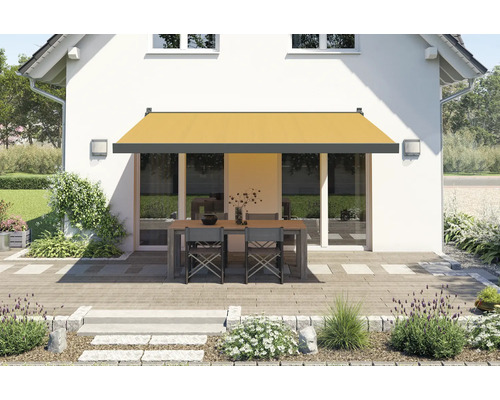 Hausfassade mit Markise über einer Terrasse mit Tisch und Stühlen
