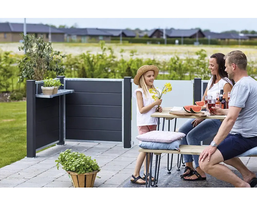 Une famille profite de son temps dans le jardin avec un brise-vue doté d''un espace de rangement.