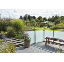 Terrasse avec paroi de protection visuelle en verre, banc et plantation dans un jardin.