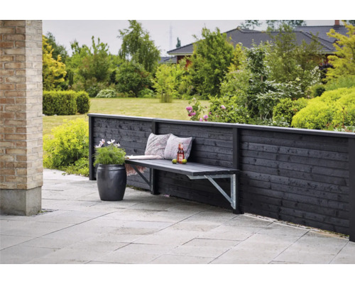Espace extérieur avec clôture en bois, banc de jardin avec coussins, boisson et jardinière