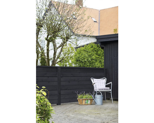 Scène de jardin avec clôture en bois, chaise de jardin, arrosoir et panier à plantes