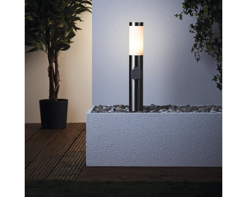 Borne lumineuse éclairée dans une jardinière remplie de pierres à côté d''une plante