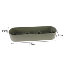 Coupe oblongue grise avec structure nervurée et quatre supports à l'intérieur, dimensions 32 par 8 par 6 centimètres.